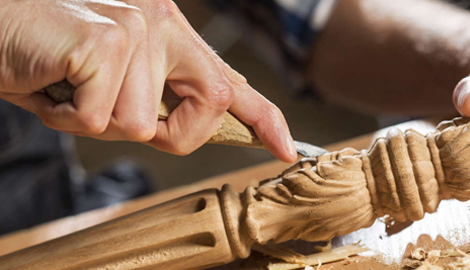 An individual is engaged in the art of wood carving, meticulously shaping a wooden object with a knife - office and dry containers