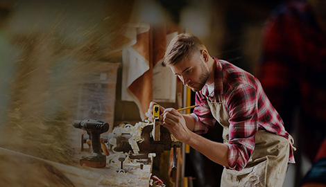 A man concentrating on a woodworking project, utilizing various tools amidst a collection of wood pieces in his workshop - office and dry containers